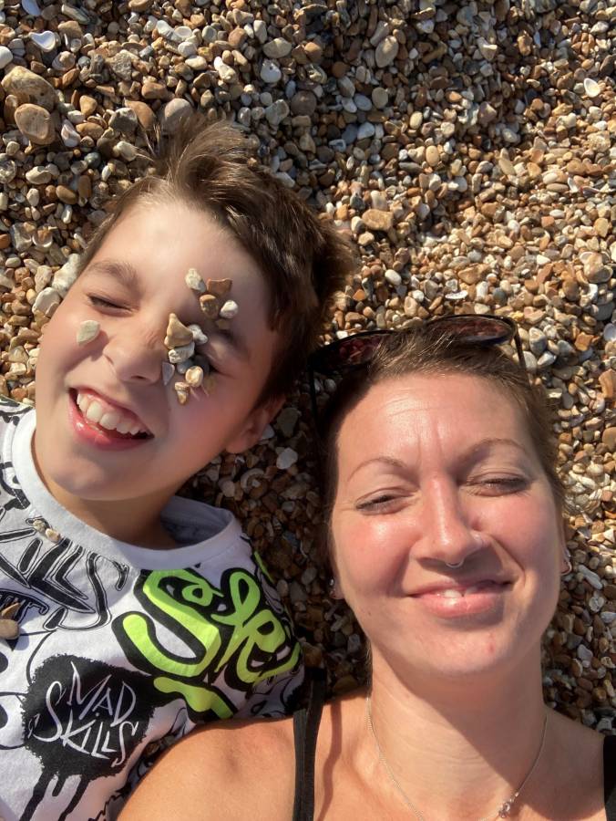 Mother and son on beach with stones on their face, smiling - Friends of Holcot