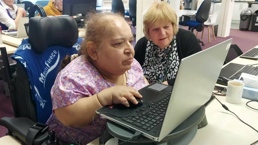 Compaid charity. One woman helping another use a laptop