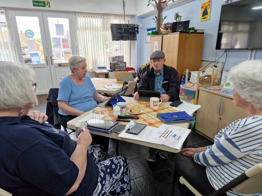 Older people around a table using tablets