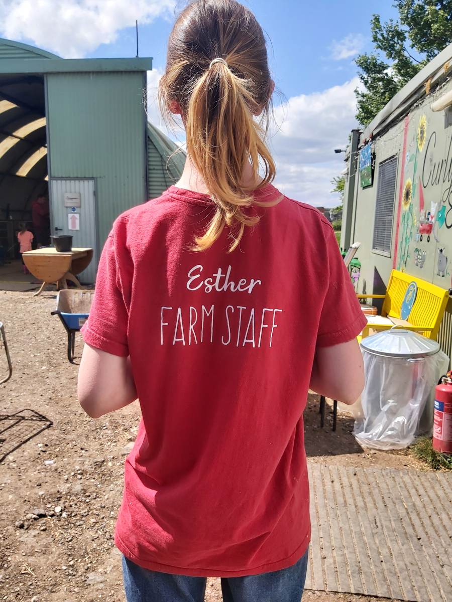 Curly’s Legacy - Esther from behind wearing farm staff t-shirt