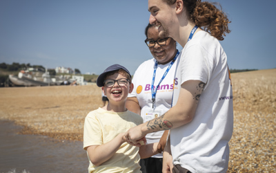We are Beams - boy laughing with 2 We are Beams tema members on the beach
