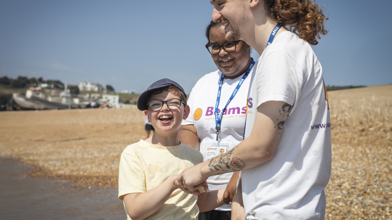 We are Beams - young laughing on the beach with two We are Beams team members