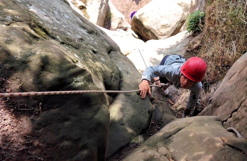 Boy rock climbing using ropes and wearing helmet