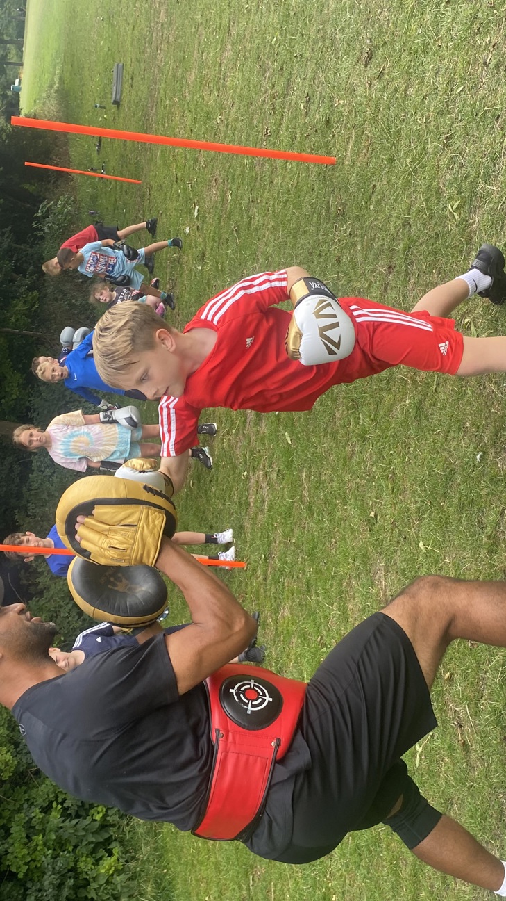A boy boxing outside with a coach
