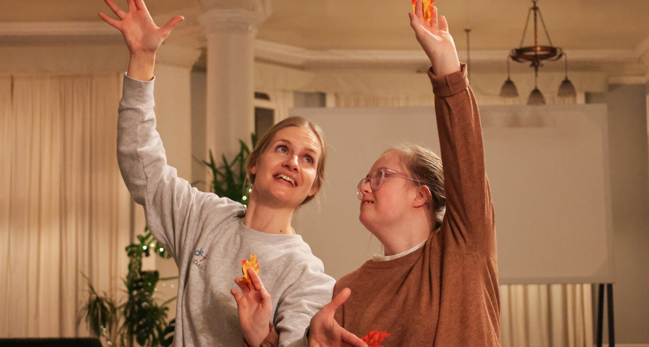 Two women dancing, each with an arm in the air.