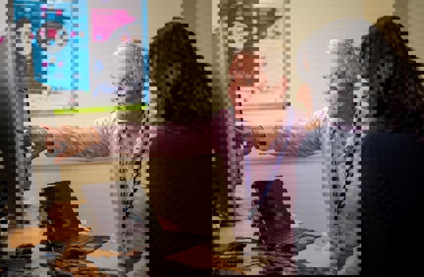 Two women pointing at a laptop screen